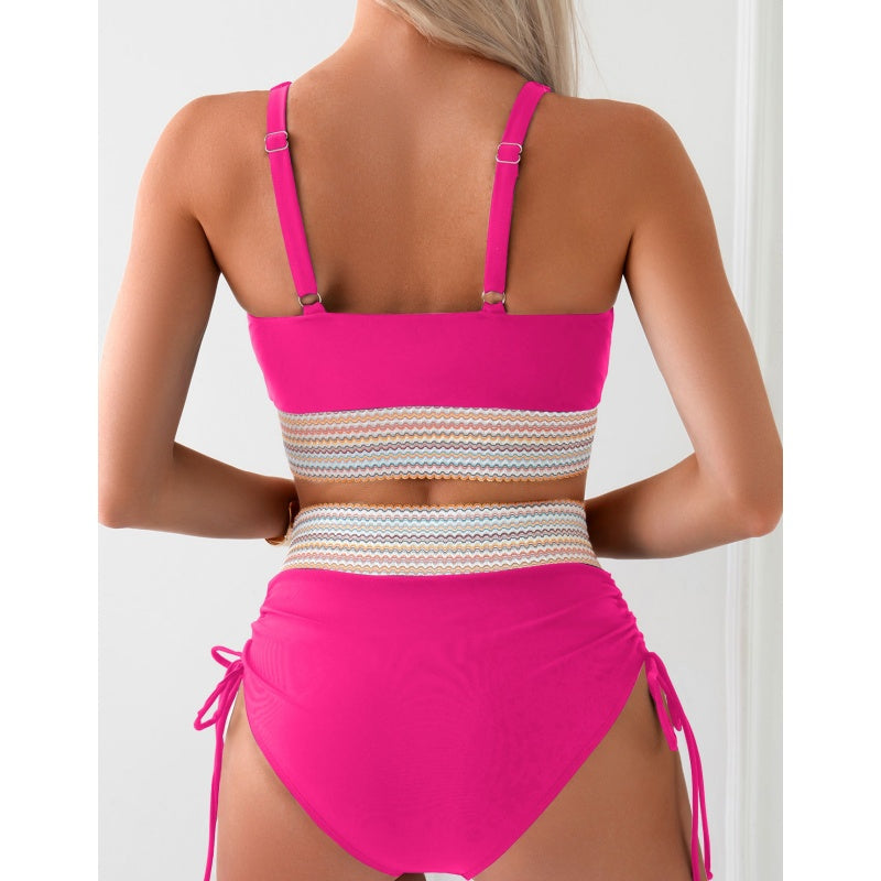 A woman is seen from the back wearing a vibrant pink high-waisted bikini set with a chic color block design. The swimsuit features adjustable straps and a decorative band around the waist, perfect for a stylish beach look.