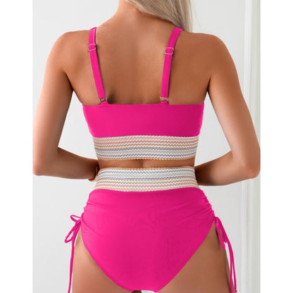 A woman is seen from the back wearing a vibrant pink high-waisted bikini set with a chic color block design. The swimsuit features adjustable straps and a decorative band around the waist, perfect for a stylish beach look.