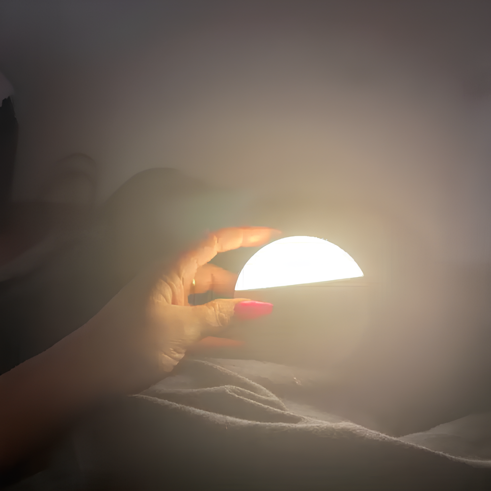 Hand holding a small round light source against a dark background